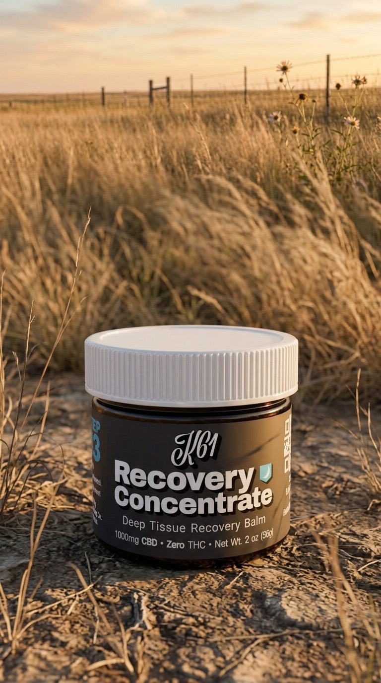 K61 Recovery Concentrate deep tissue balm jar in Kansas prairie grass at golden hour, beside a barbed wire fence line
