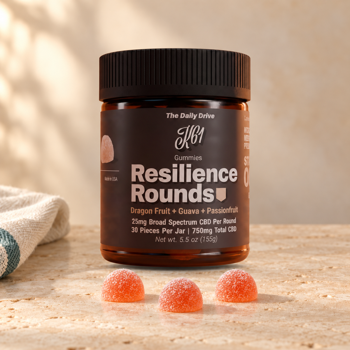 K61 Resilience Rounds gummies jar on warm travertine stone with three gummies in front, 25mg broad spectrum CBD per round